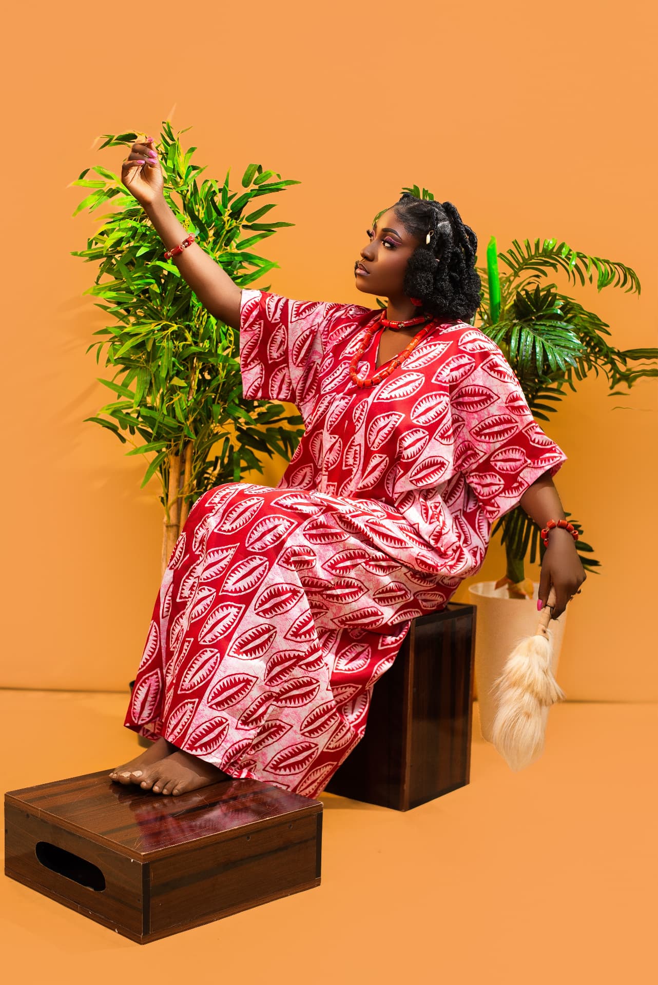 Model in red and white patterned Ankara against an orange backdrop