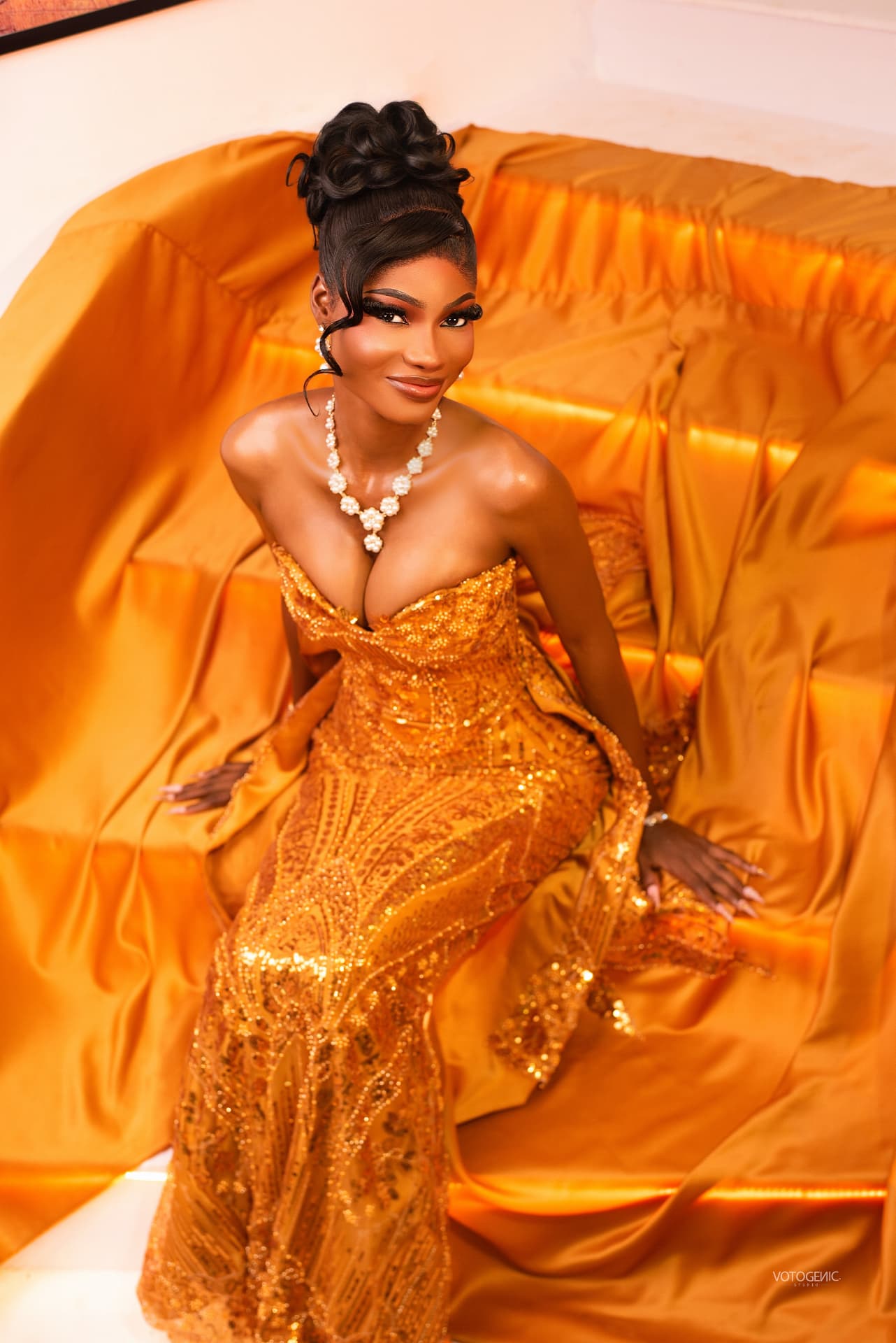 Model in a gold sequin gown on gold satin